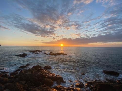 a sunset over the ocean with rocks in the water at Apto Cielo Azul in Manuel Antonio