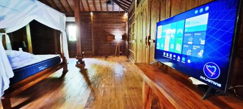 1 dormitorio con TV de pantalla grande y 1 cama en VILLA LE PETIT LEON "Authentic Traditional Wooden House", en Buleleng