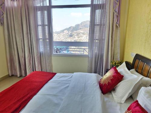 een slaapkamer met een bed en een groot raam bij Hillside 3BHK with PanoramicView in Solan