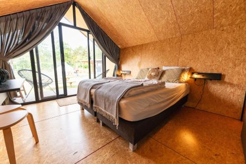 a bedroom with a bed and a large window at Tenthuisje met hottub in Callantsoog in Callantsoog