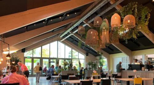 un restaurante con mesas y personas sentadas en mesas en Tenthuisje met hottub in Callantsoog, en Callantsoog