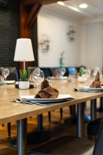 a wooden table with glasses and napkins on it at Logis Hôtel Des Acacias Lille Neuville en Ferrain, Restaurant l'Acacias Gourmand in Neuville-en-Ferrain