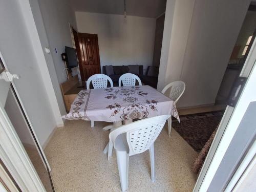 une table blanche avec quatre chaises et un tissu de table rose dans l'établissement Bienvenue dans votre appartement, à Gabès