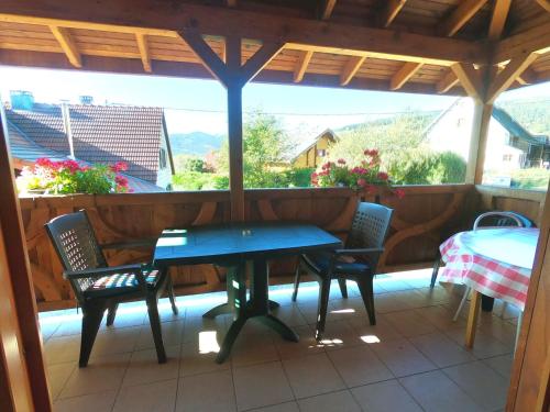 une table bleue et des chaises sur une terrasse couverte avec une table et une table dans l'établissement Appartement chaleureux à Soultzeren avec vue sur montagne, à Soultzeren
