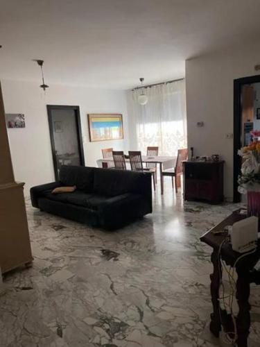 Una sala de estar con un sofá negro y una mesa. en Casa vacanze Lorien, en Génova
