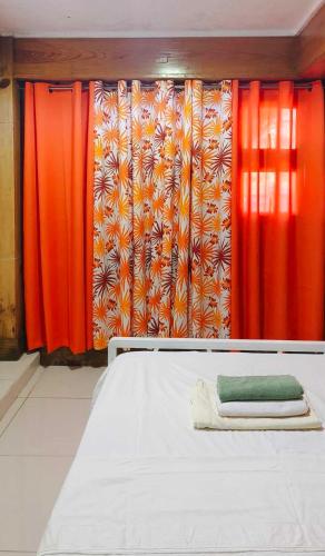 a bed in a room with red and orange curtains at Sassy's Place in Baguio
