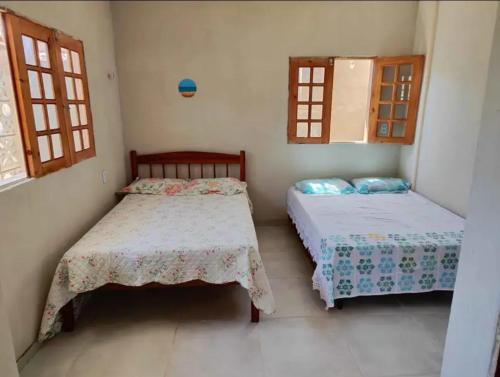 two beds in a room with two windows at Kitnet Tibau in Tibau