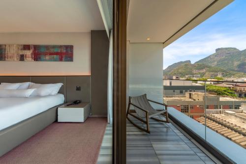 a bedroom with a balcony with a bed and a chair at Lifestyle Laghetto Collection in Rio de Janeiro