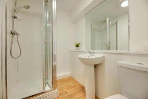 a white bathroom with a shower and a sink at Charltons Bonds Apartments 14 by Week2Week in Newcastle upon Tyne