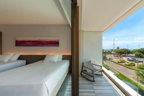 a bedroom with a balcony with a bed and a window at Lifestyle Laghetto Collection in Rio de Janeiro