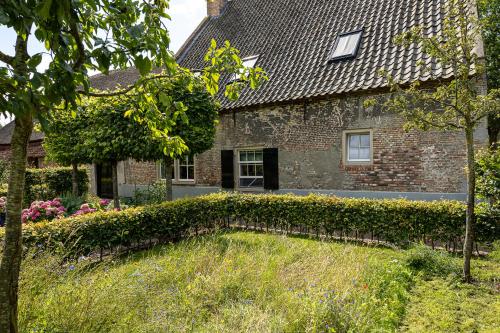 a brick house with a hedge in front of it at Den Eijngel bed and breakfast in Boxtel