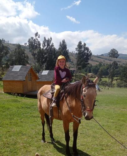 a young girl sitting on a horse in a field at Hospedaje Guatavita cabaña tippie in Guatavita