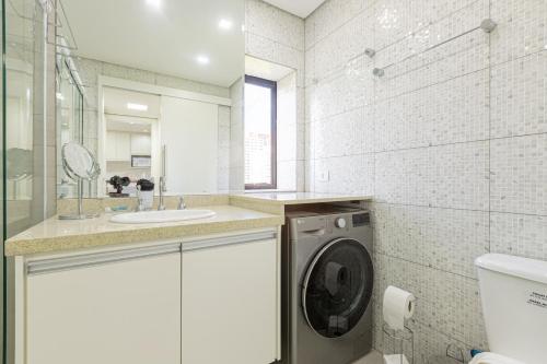 a bathroom with a washing machine and a sink at BGV - Le Bougainville By Anora Spaces in Barueri
