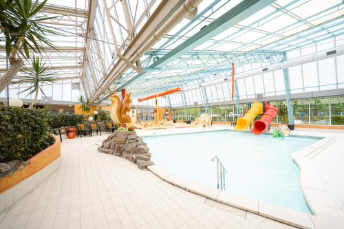 a large indoor swimming pool with a water park at Glamping Ackersate in Voorthuizen