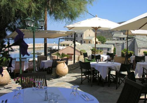 a restaurant with white tables and chairs and umbrellas at Hotel-Restaurant Le Vieux Moulin in Centuri