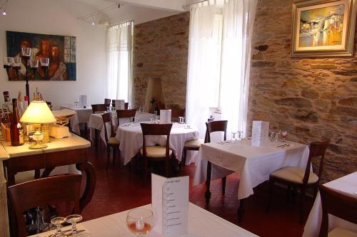 a restaurant with white tables and chairs and a stone wall at Hotel-Restaurant Le Vieux Moulin in Centuri