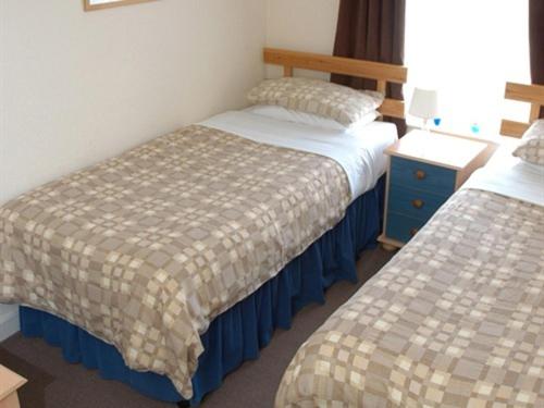 a hotel room with two beds and a night stand at Kentmere Guest House in Folkestone