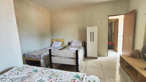 チバウ・ド・スーにあるcasa pra muito genteのベッドルーム1室(ベッド2台付)、廊下へのドアが備わります。