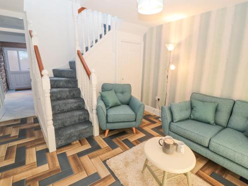 a living room with two chairs and a staircase at Hillside Hideaway in Wigton