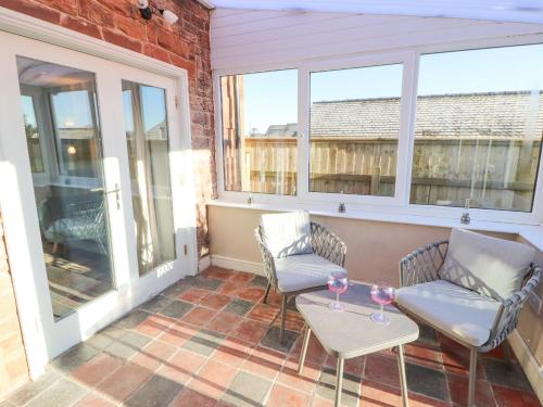 a patio with two chairs and a table and windows at Hillside Hideaway in Wigton