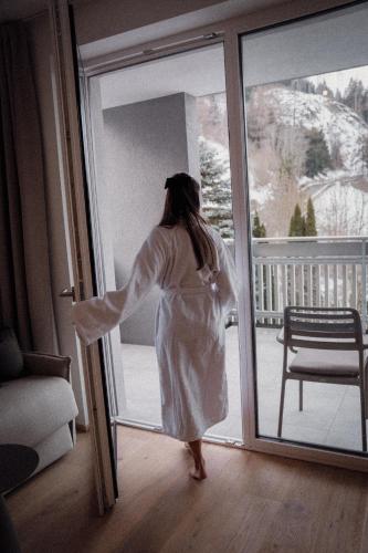 a woman in a white dress looking out of a door at Anett hotel in Vipiteno