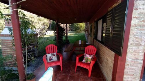 Duas cadeiras vermelhas e uma mesa no alpendre. em AbbeyHouse descanso y vacaciones em Victoria