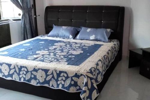 a bed with a blue and white blanket and pillows at Luxury Bungalow in Senawang in Seremban