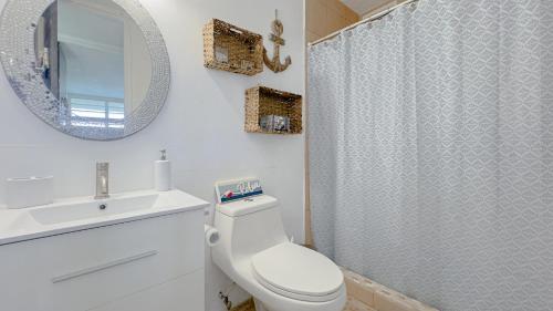 y baño con aseo, lavabo y espejo. en Moana's Beach Apartment in Luquillo PR Beach View, en Luquillo