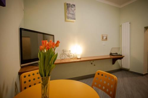 Cette chambre comprend une table et un vase avec des fleurs orange. dans l'établissement Casetta Ponte Milvio, à Rome
