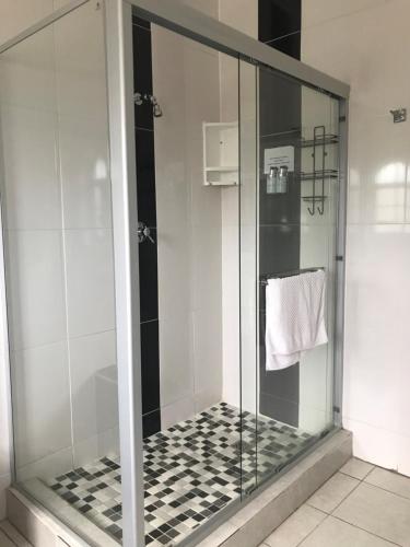 a glass shower with a black and white checkered floor at Fairway Guest Lodge in Margate