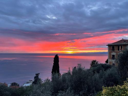 a sunset over the ocean with a building on a hill at Villa Mortola in Camogli
