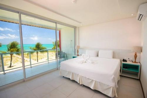 a bedroom with a bed and a view of the beach at Hotel Praia Dourada in Maragogi