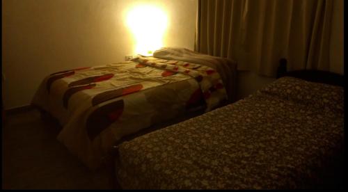 ein Schlafzimmer mit 2 Betten und einer Lampe an der Wand in der Unterkunft AbbeyHouse descanso y vacaciones in Victoria