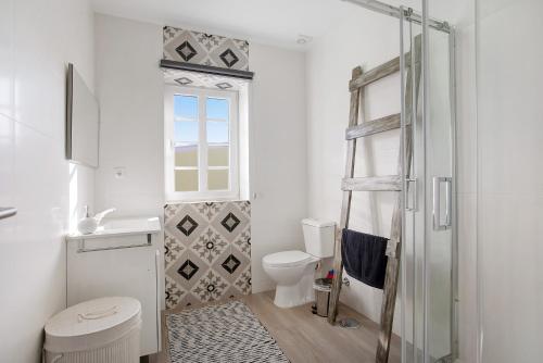 La salle de bains est pourvue de toilettes et d'une douche en verre. dans l'établissement Casa Davó, à Leiria