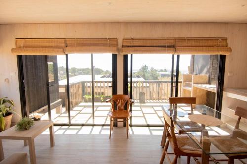 a living room with a glass table and chairs at Kinesurf cabaña con vista al mar in Pichilemu