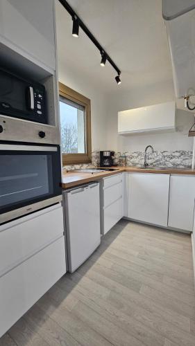 une cuisine avec des armoires blanches et un micro-ondes dans l'établissement Le Jude - studio - lumineux, à Vannes