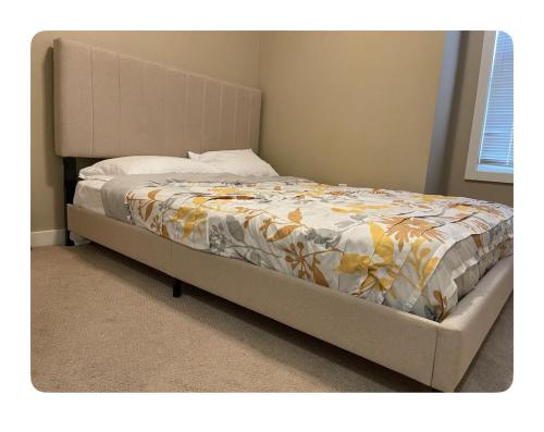 a bed with a yellow and white comforter on it at Edmonton in Edmonton