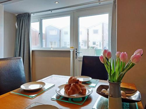 a table with a vase of flowers and a vase of tulips at Swn Y Tonnau in Tywyn