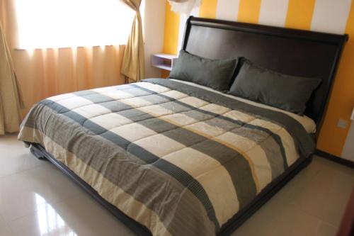 um quarto com uma cama com um edredão listrado em Lux Suites Milimani Executive Apartments Nakuru em Nakuru