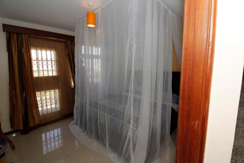 um quarto com uma cama com cortinas brancas em Lux Suites Milimani Executive Apartments Nakuru em Nakuru
