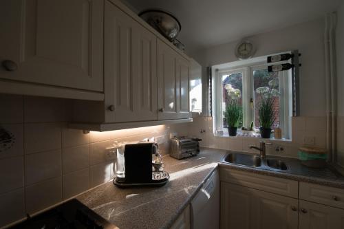 a kitchen with white cabinets and a toaster on the counter at 4 Bed Townhouse 2 mins from everything & 1 parking space! in Stratford-upon-Avon
