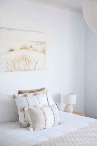 a white bedroom with a bed with white sheets and pillows at ChelseaVue - Designer Beachside Townhouse Retreat in Chelsea