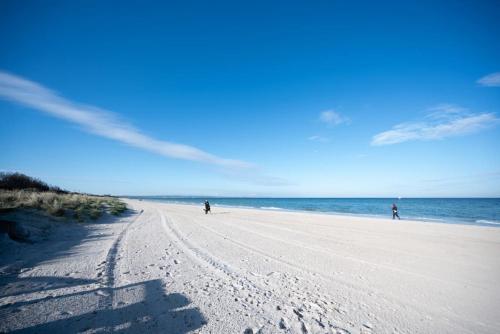 two people walking on a sandy beach near the ocean at ChelseaVue - Designer Beachside Townhouse Retreat in Chelsea