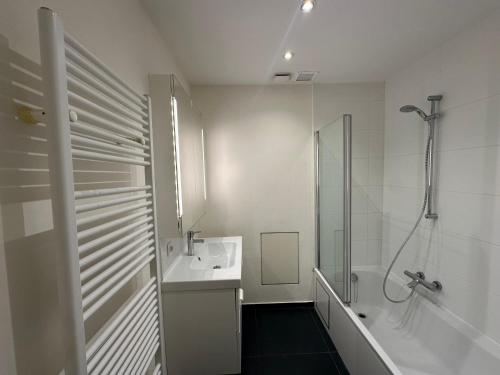 une salle de bain blanche avec une douche et un lavabo dans l'établissement Spacious Apartment next to Port of Antwerp, à Anvers