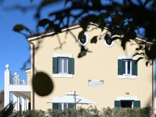 un bâtiment avec des fenêtres vertes à volets et un arbre dans l'établissement DON PEPPE ROOMS : Villaggio Green, à SantʼAngelo in Formis