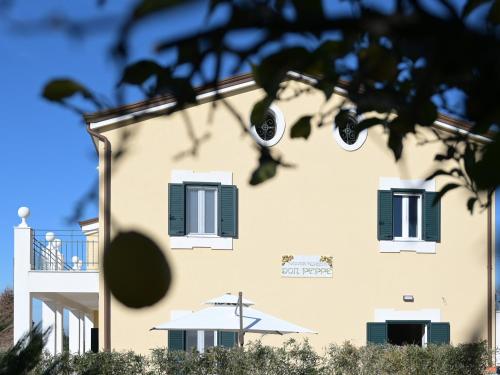 a building with green shuttered windows and a tree at DON PEPPE ROOMS : Villaggio Green in SantʼAngelo in Formis