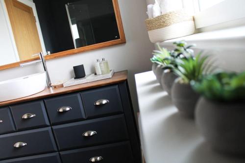 a bathroom with a sink and a dresser with a mirror at Seagrass a luxurious gem by the sea in Youghal