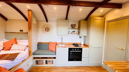 a tiny house with a kitchen and a bed in it at The Dragonfly - Luxury Lakeside Shepherds Hut in Cotham