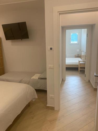 a bedroom with two beds and a television on the wall at DON PEPPE ROOMS : Villaggio Green in SantʼAngelo in Formis