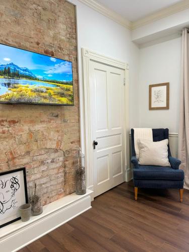 a living room with a blue chair and a brick wall at Garden on Capital-Bourbon & Horse Country in Frankfort